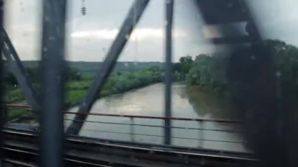 Tåget går över bron över floden. Utsikten från fönstret. — Stockvideo