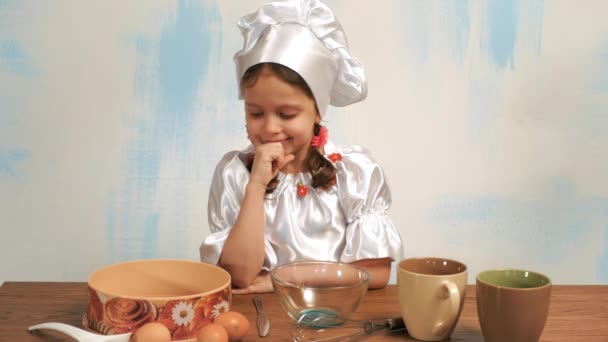 Menina em terno e chapéu do chef escolhe o ovo e sorrindo . — Vídeo de Stock