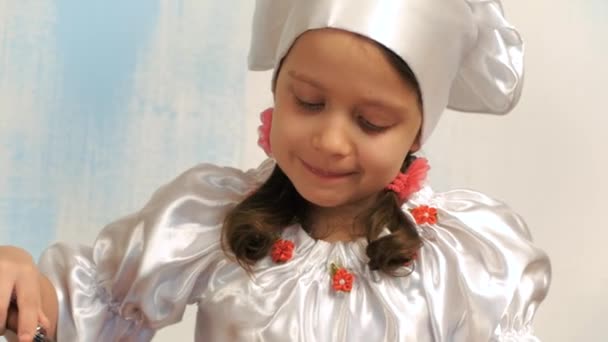 Schöne kleine Mädchen im Hut des Chefs mischen Eier und Zucker. — Stockvideo