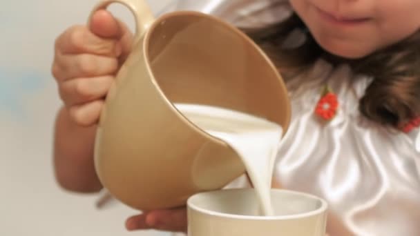 Mädchen im Hut des Chefs gießt Milch in eine Tasse — Stockvideo