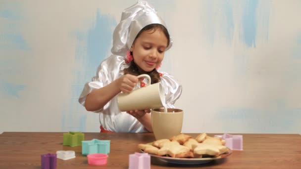 Mädchen im Hut des Chefs gießt Milch in eine Tasse — Stockvideo