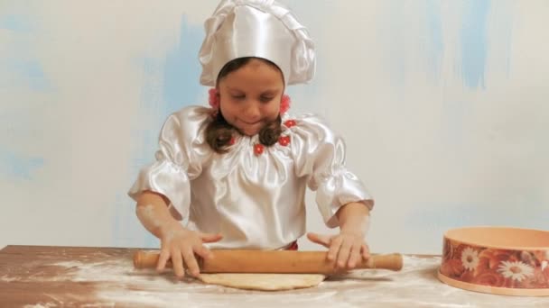 Girl chef with rolling pin knocking on palm and kneads the dough on table. — Stock Video