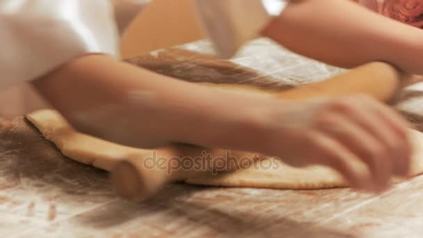 Дівчата руками з прокатним штифтом замішують тісто на столі крупним планом . — стокове відео