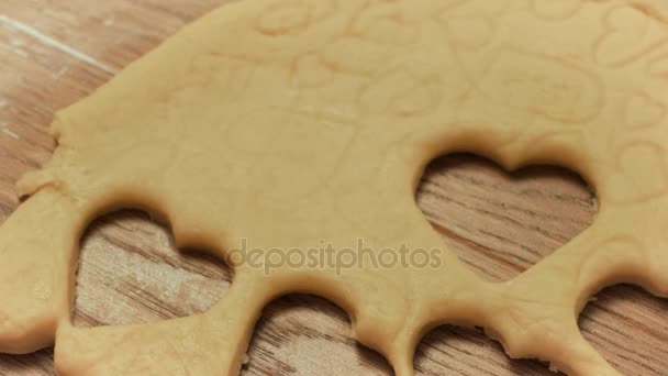 Kind handen maken van cookies van ruwe deeg in de vorm van hart, close-up. — Stockvideo
