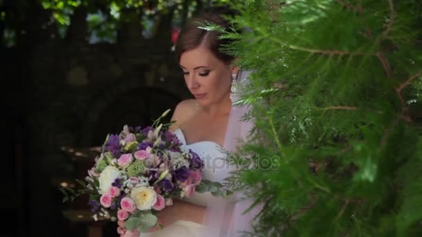 Unga vackra bruden håller en bukett blommor. Porträtt av en charmig tjej. — Stockvideo