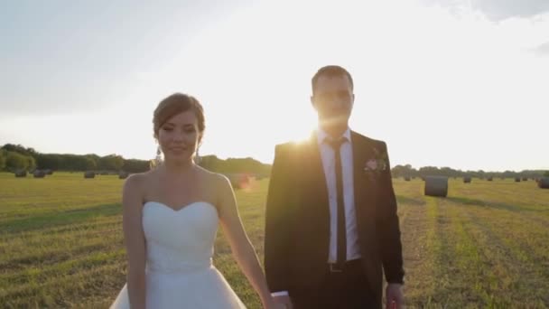 Mariée et marié sont sur le terrain au coucher du soleil. Un couple amoureux . — Video