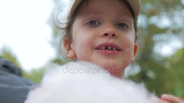 La fille dans le chapeau sans une dent manger des barbe à papa, gros plan . — Video