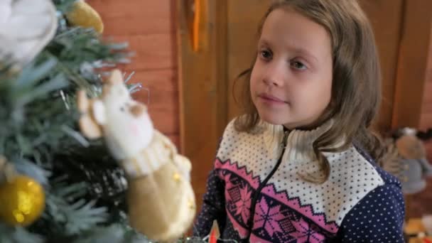 Jong meisje in de hoed kerstboom ornament te zetten — Stockvideo
