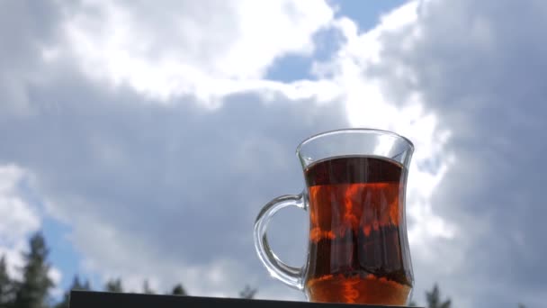 Рука берет чашку чая на фоне облаков . — стоковое видео