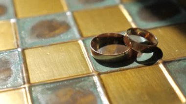Wedding rings on a brass copper chessboard, close-up