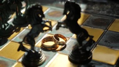 Silhouette of chess horses and wedding rings on the chessboard. Close up