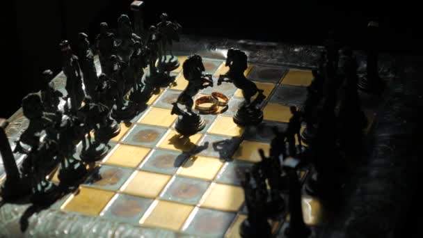 Silhouette of chess horses and wedding rings on the chessboard. Close up — 图库视频影像