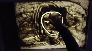 Sand animation. Child drawing sand on a white screen with hands