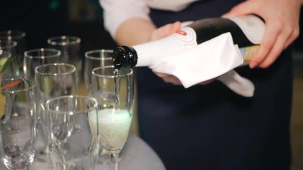 Serveersters handen gieten champagne in glazen voor de bruiloft, close-up. Bubbels mousserende wijn in een helder glas — Stockvideo