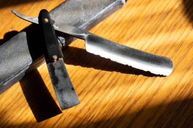 Ahşap bir arka planda saç kesimi için tehlikeli bir jilet..