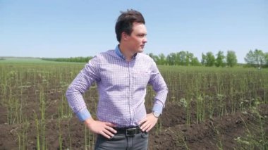 Ekose gömlekli cesur adamın portresi kuşkonmaz tarlasında duruyor, önünde el ele tutuşuyor ve mutlu bir şekilde gülümsüyor..