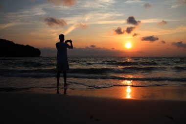 Siluet fotoğrafçı sahilde Sunrise fotoğraf çekmek.