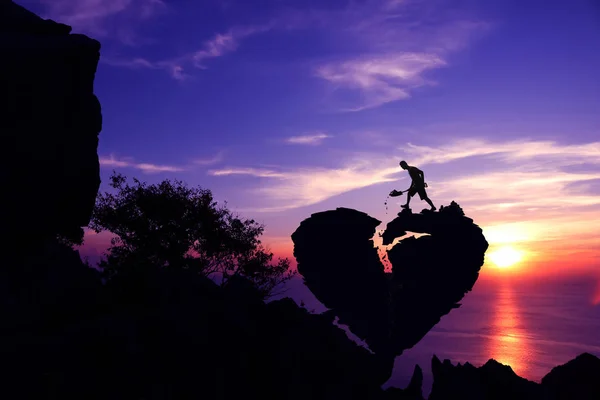 День святого Валентина концепции, человек лопатой камень для ремонта разбитого сердца форме скалы на горе . — стоковое фото