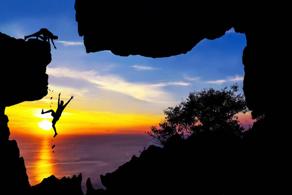 Человек помогает другу, который упал с скалолазания
.