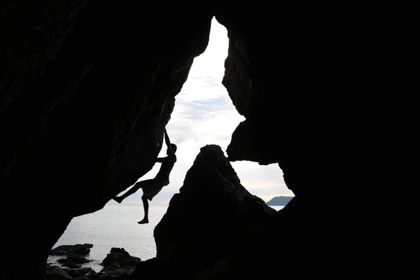 Człowiek wspiąć się między skały w pobliżu oceanu. — Zdjęcie stockowe