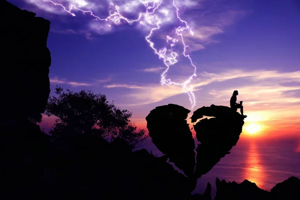 Sevgililer günü, kırık kalp şeklindeki taş mor gökyüzü günbatımı arka plan ile bir dağda kadınlar oturmak.