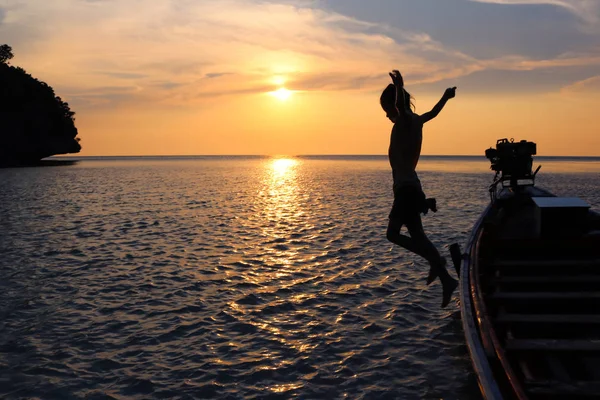 Silueta niñas saltar de un barco de cola larga con puesta de sol . — Foto de Stock