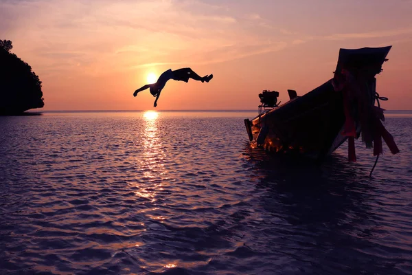 Silhouette filles sauter d'un bateau dans la mer épisode coucher de soleil, Somersault à l'océan — Photo