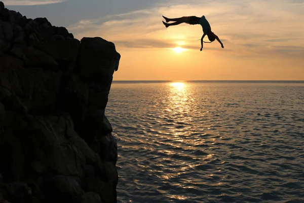 Aziatische meisjes springen van een rots in de zee aflevering zonsondergang, Salto naar de Oceaan — Stockfoto