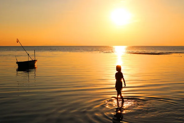 Silhouette fille a marché sur la plage avec un bateau de pêche et coucher de soleil . — Photo
