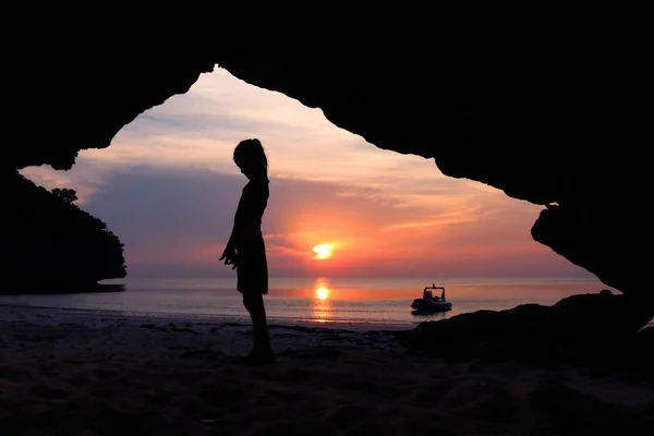 Silueta niñas de pie en frente de una cueva en la playa . — Foto de Stock