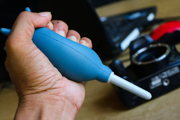 Una mano con el ventilador está limpiando la cámara . — Foto de Stock