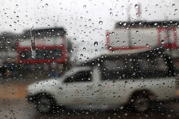 Regentropfen auf eine Autoscheibe auf der Straße. — Stockfoto