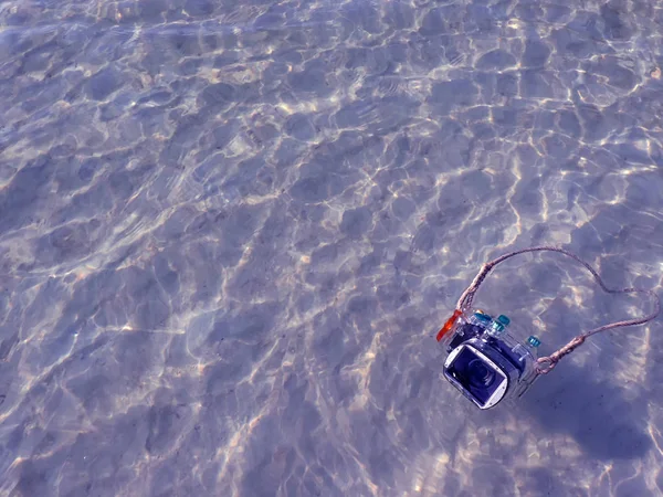 Compact camera and housing floating on the sea.