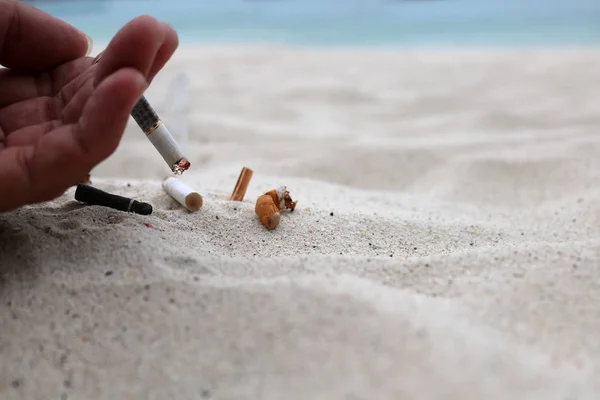 Mano fumar cigarrillo y cenicero en la playa —  Fotos de Stock