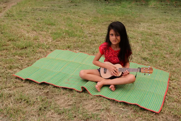 Tajski Dziewczyna grając ukulele w ogrodzie. — Zdjęcie stockowe