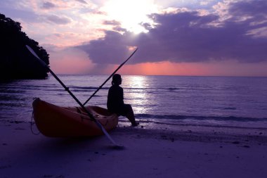 Mavi gökyüzü günbatımı arayan turist kızla sahilde Kayak siluet.