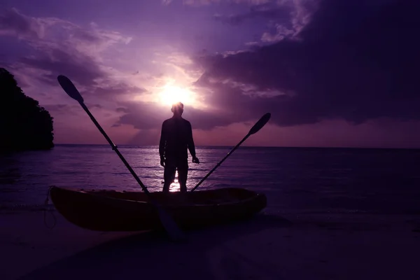 Silueta kayak en la playa con el hombre mirando el atardecer . — Foto de Stock