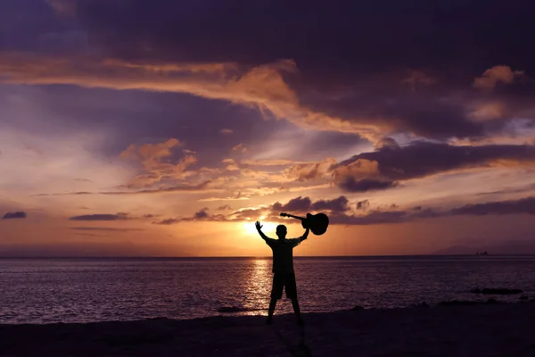 Los hombres y la guitarra en la playa con un cielo púrpura amanecer . —  Fotos de Stock