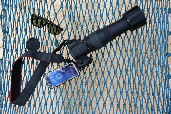 Mobiltelefon med kamera och solglasögon på stranden — Stockfoto