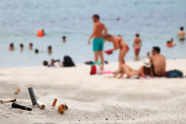 Sigaretten peuken asbak op het strand met toeristen door de zee. — Stockfoto