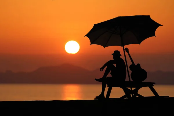 Silhouet van een man een gitaar spelen op het strand — Stockfoto