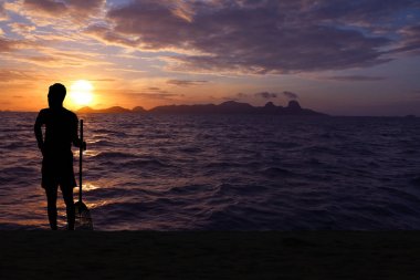 Siluet Asya adam temiz plaja bambu süpürgeler
