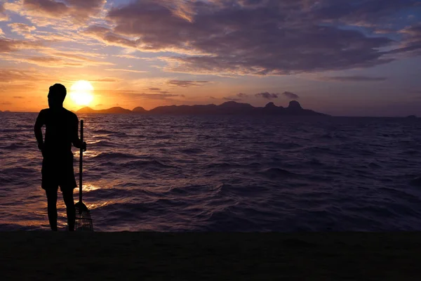Siluet Asya adam temiz plaja bambu süpürgeler