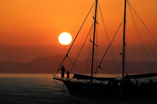 Famiglia Silhouette sullo yacht con cielo rosso tramonto — Foto Stock