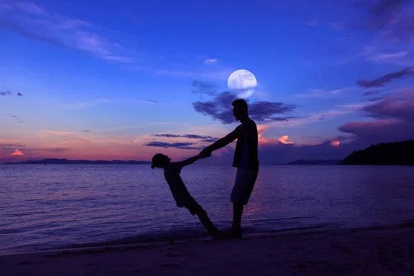 Silhouet vader en dochter op het strand met de lucht van de maan — Stockfoto