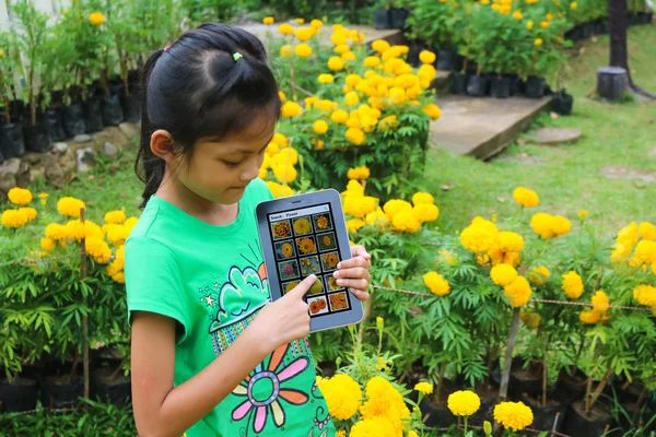 Azjatycka dzieci poszukiwania gatunków kwiatów przez tablet w gar — Zdjęcie stockowe