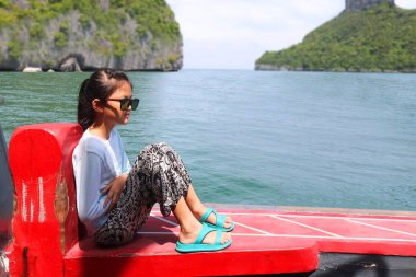 Asyalı kız okyanus doğa manzaralı bir teknede oturuyor