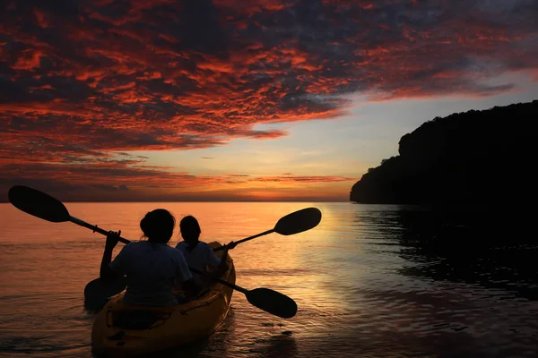 Mother and daughter kayaking in the ocean with red sky sunset — Stock Photo, Image