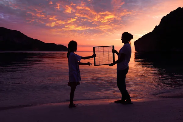 Anya és lánya a strandon, a vörös ég naplemente — Stock Fotó