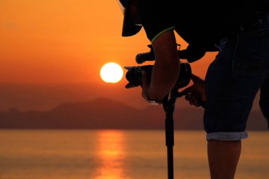 Kameramanların sahilde okyanus ve Günbatımı ile akşam 